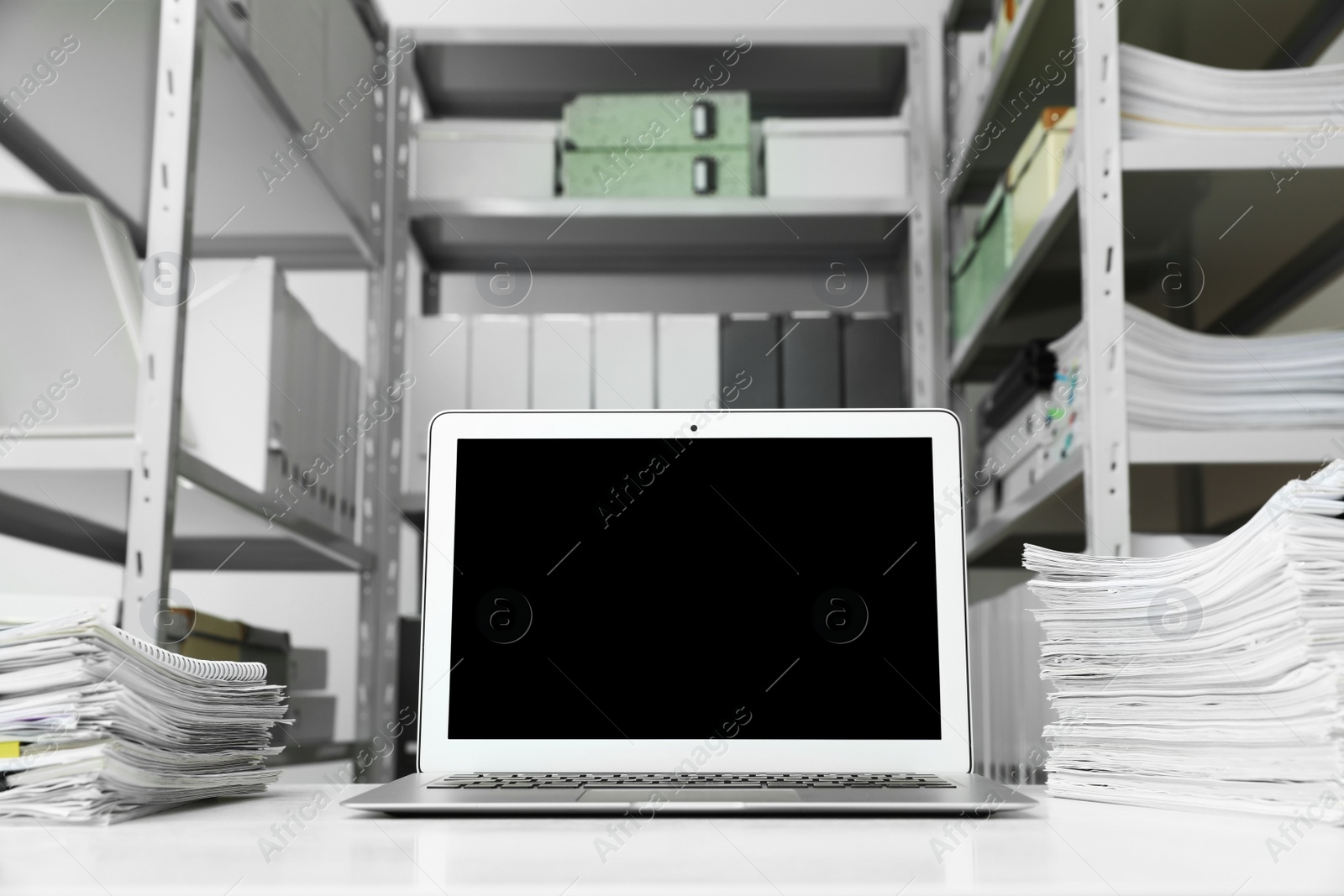 Photo of Laptop and documents on desk in office. Space for text