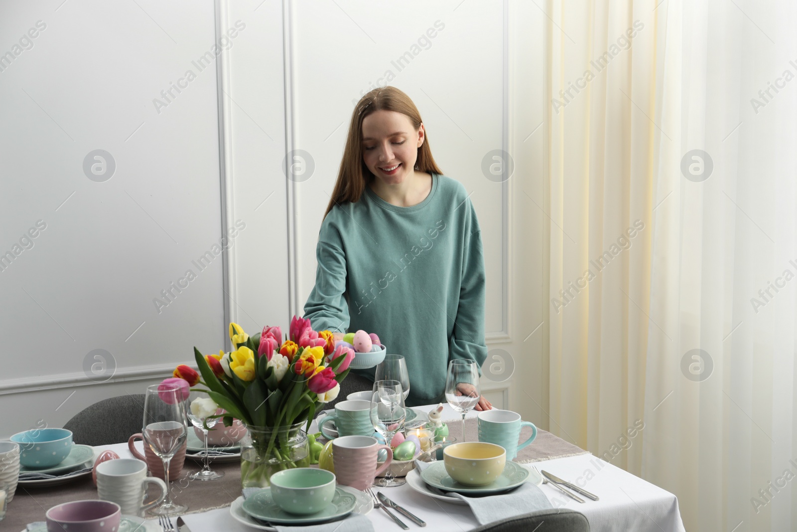 Photo of Woman setting table for festive Easter dinner at home