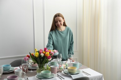 Woman setting table for festive Easter dinner at home