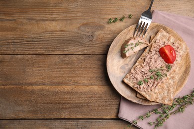 Crispy crackers with delicious meat pate and thyme served on wooden table, flat lay. Space for text