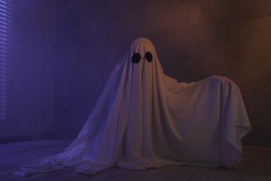 Photo of Creepy ghost. Woman covered with sheet in color lights