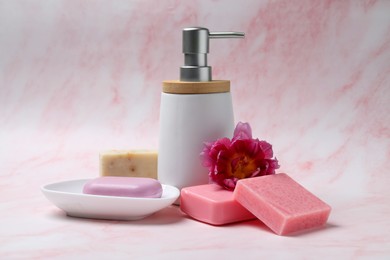 Photo of Soap bars and bottle dispenser on pink marble background