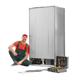 Male technician repairing refrigerator on white background