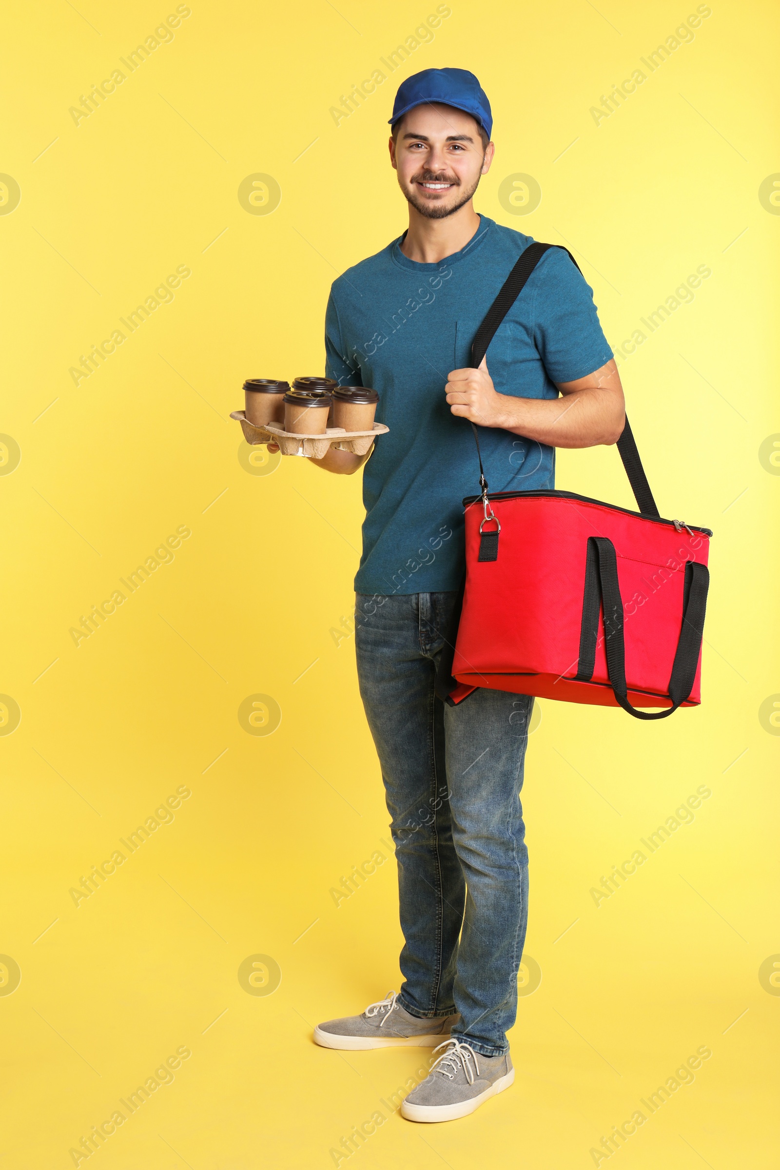 Photo of Young courier with thermo bag and drinks on color background. Food delivery service
