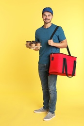 Young courier with thermo bag and drinks on color background. Food delivery service