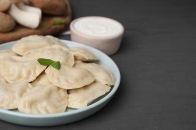 Plate of delicious dumplings (varenyky) with mushrooms on grey wooden table, closeup. Space for text