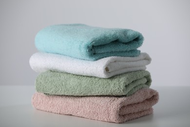 Photo of Stack of folded soft colorful towels on white table