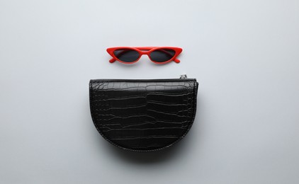 Photo of Stylish woman's bag and sunglasses on light background, flat lay