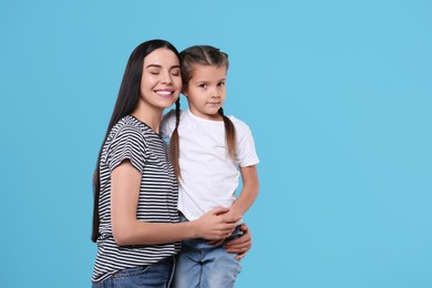 Happy woman with her cute daughter on light blue background, space for text. Mother's day celebration