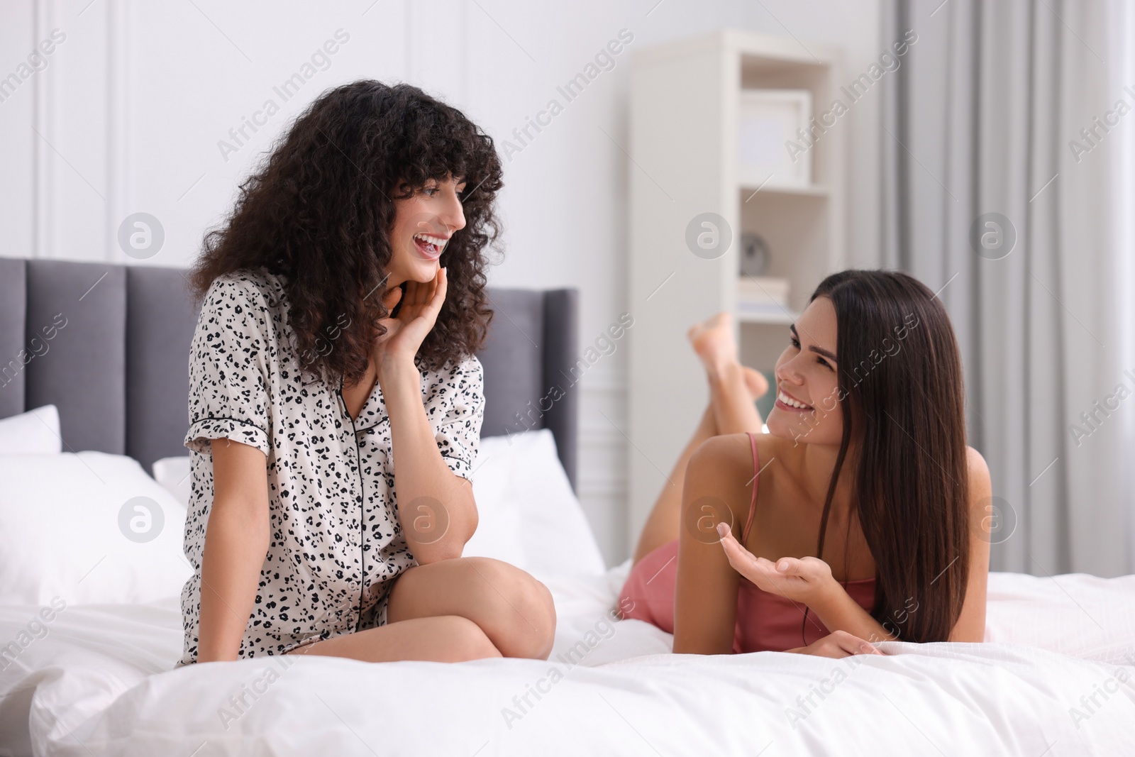Photo of Happy young friends spending time together on bed at home
