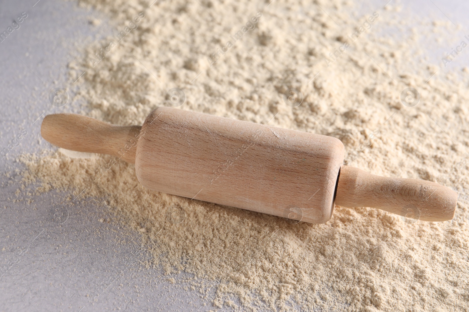 Photo of Rolling pin and scattered flour on light textured table, closeup