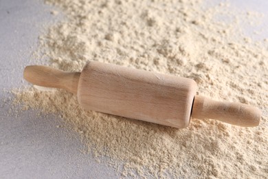 Photo of Rolling pin and scattered flour on light textured table, closeup