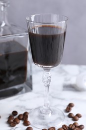 Coffee liqueur and beans on white marble table, closeup