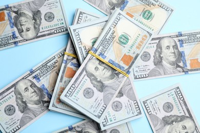 Photo of Many dollar banknotes on light blue background, flat lay