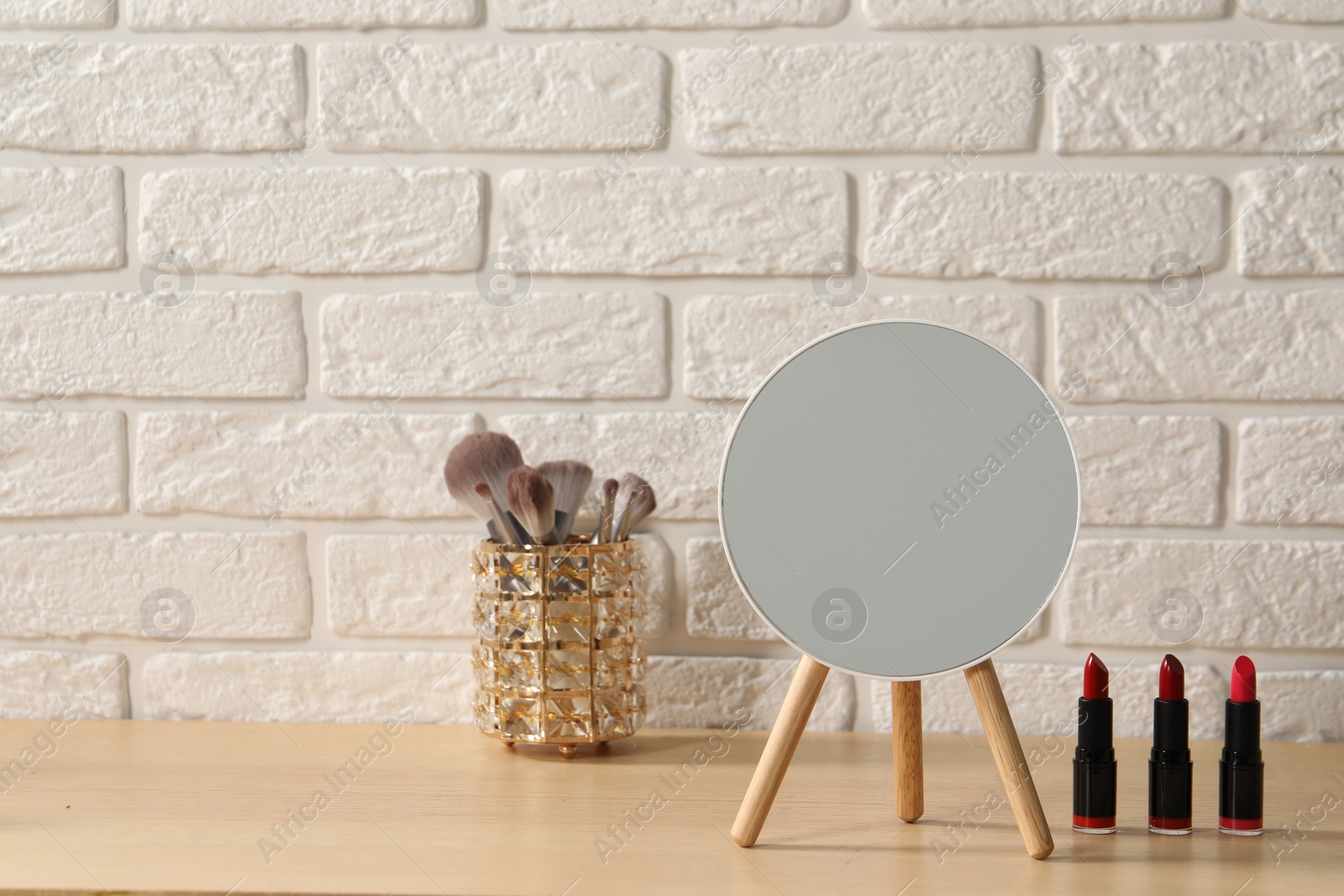 Photo of Mirror and makeup products on wooden dressing table in room. Space for text