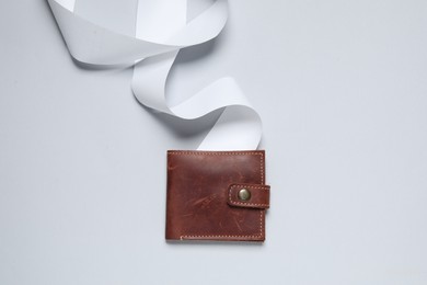 Photo of Brown leather wallet and thermal paper for receipt on light grey background, top view