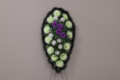Photo of Funeral wreath of plastic flowers on grey background