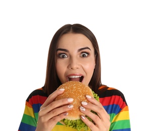 Young woman eating tasty burger on white background