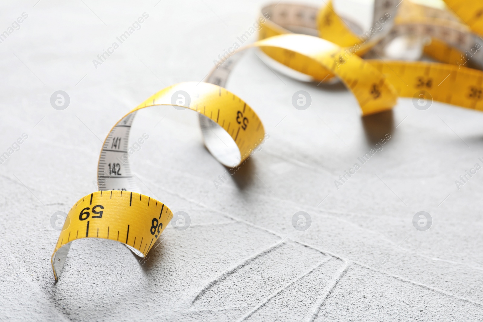 Photo of Measuring tape on grey background, closeup. Tailoring equipment