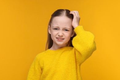Little girl suffering from headache on yellow background
