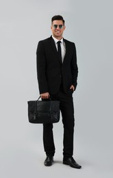 Photo of Businessman with stylish leather briefcase on light background