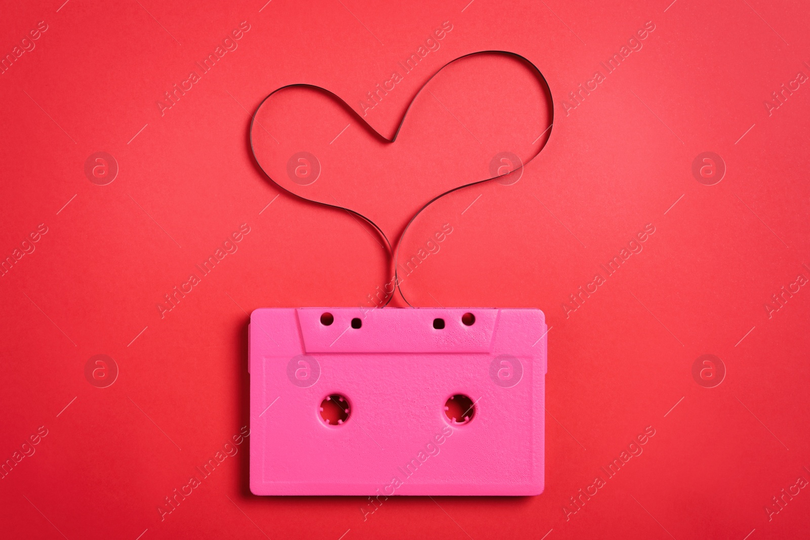 Photo of Music cassette and heart made with tape on red background, top view. Listening love song