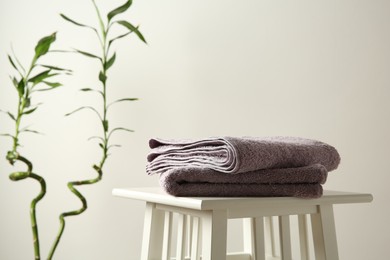 Photo of Violet towels on stool against white wall. Space for text