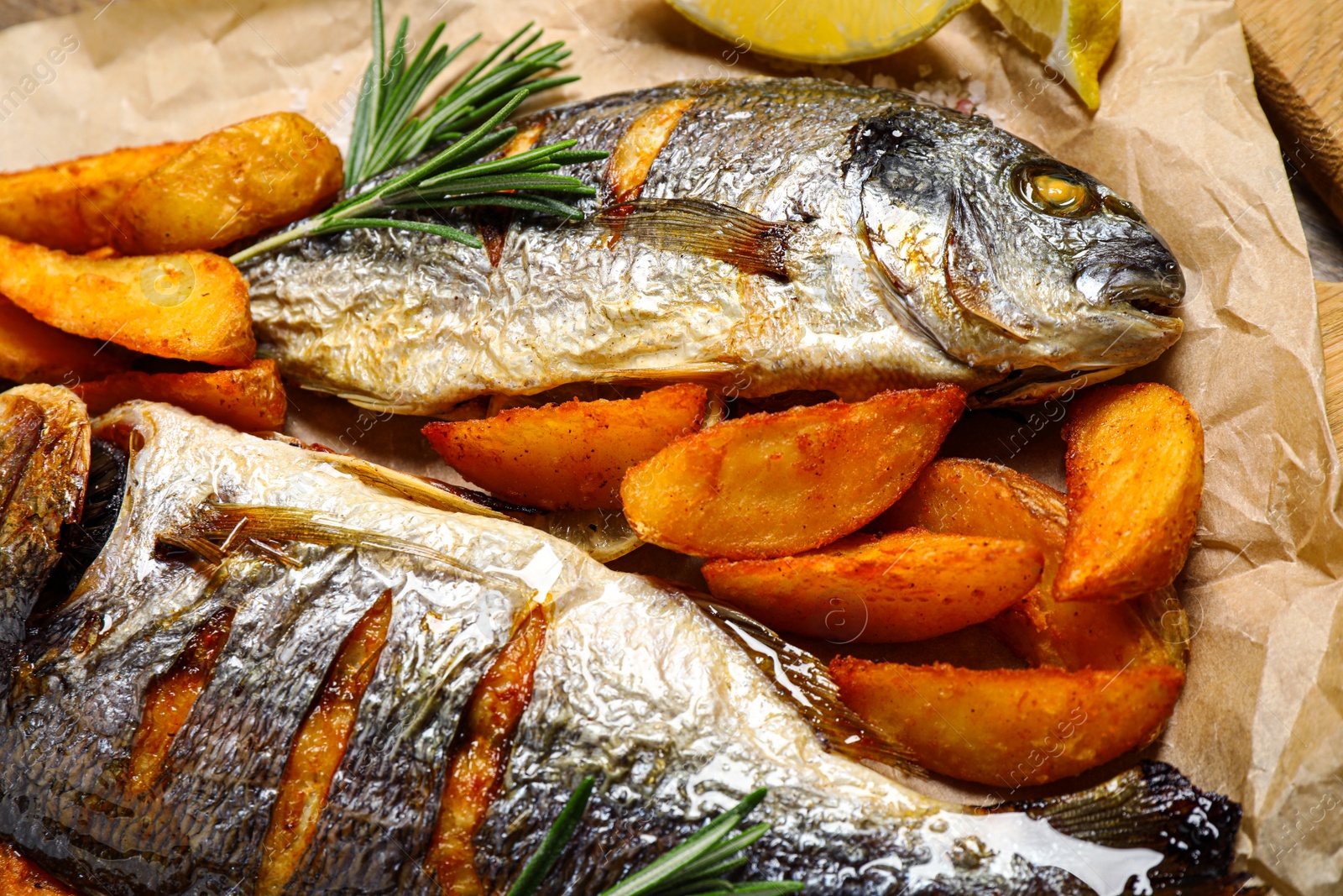 Photo of Delicious roasted fish and potatoes on parchment paper, closeup