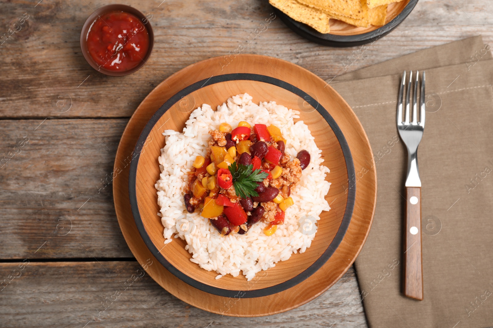 Photo of Chili con carne served with rice and sauce on wooden table, top view