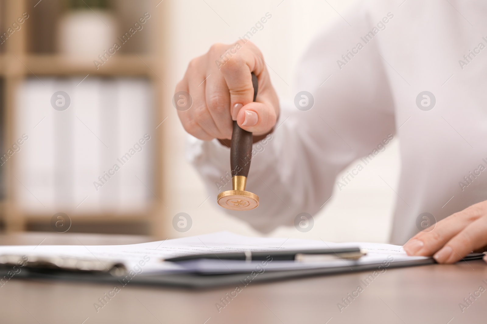 Photo of Woman stamping document at table, closeup view