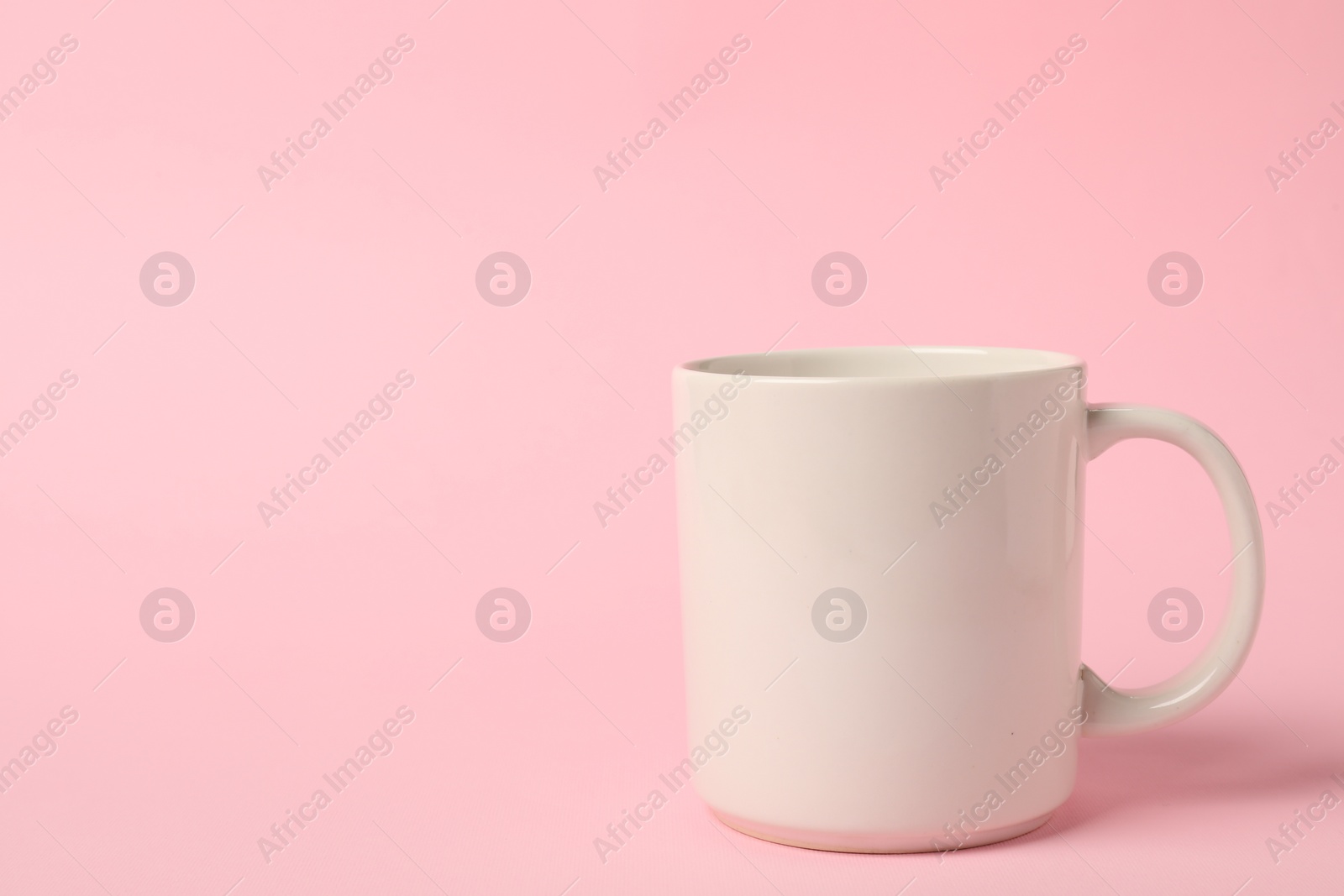 Photo of One white ceramic mug on pink background, space for text