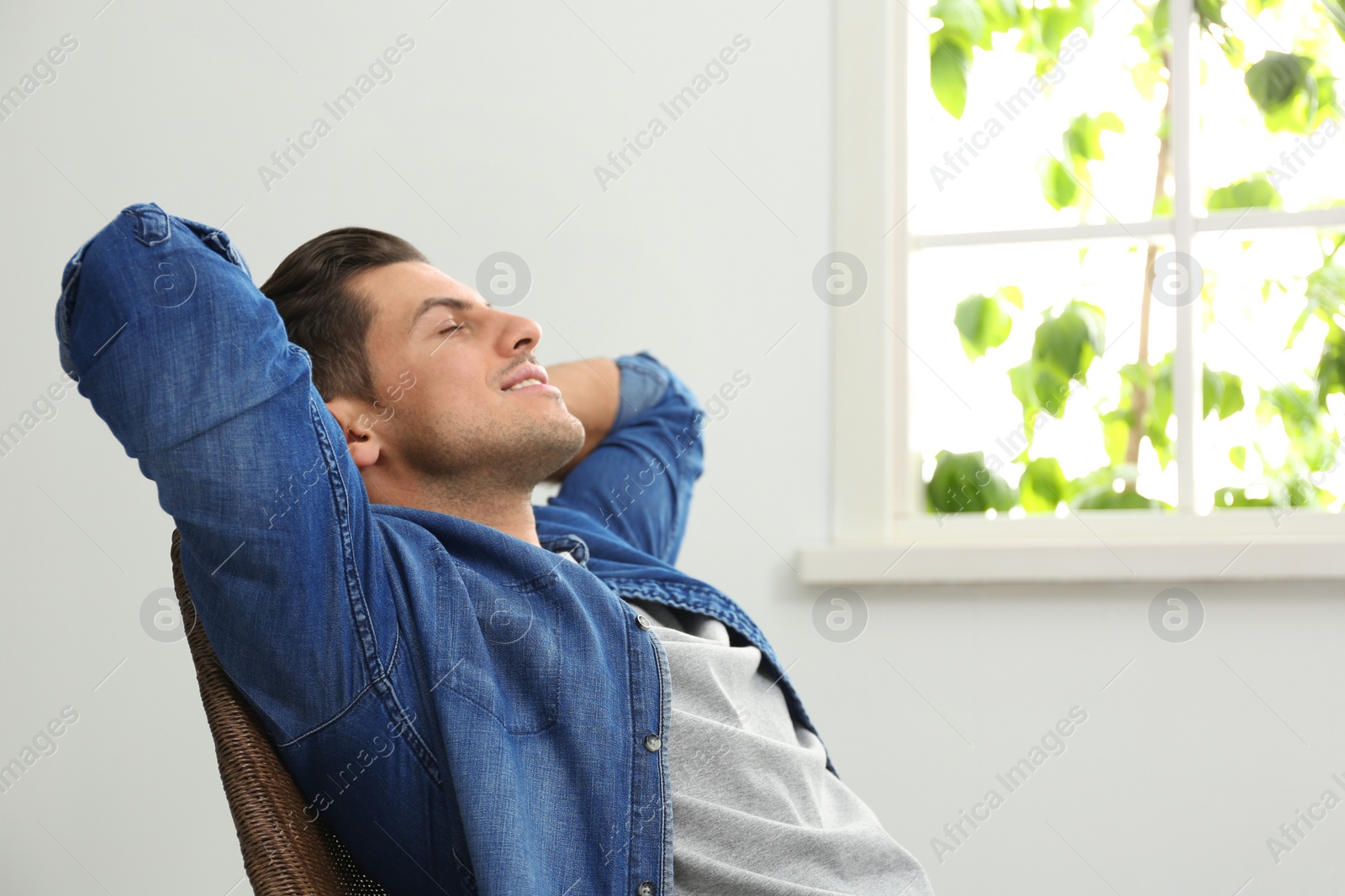 Photo of Attractive man relaxing in armchair near window at home