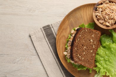 Photo of Delicious sandwich with tuna and lettuce leaves on white wooden table, top view. Space for text