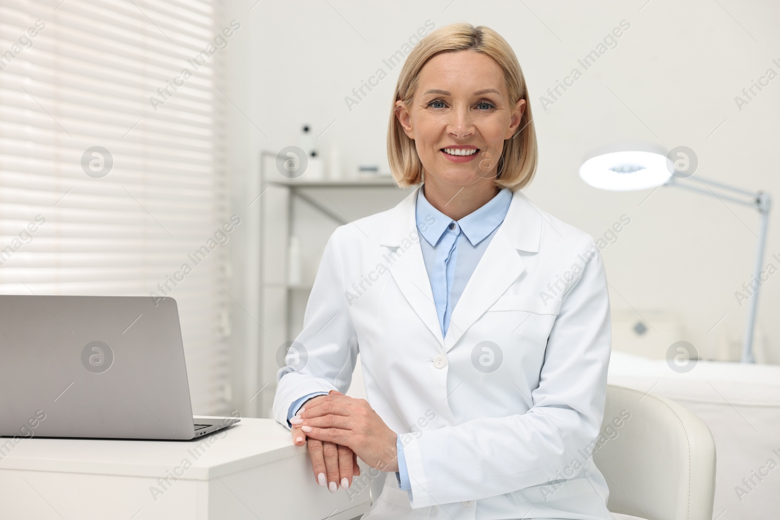 Photo of Portrait of happy dermatologist at white table in clinic