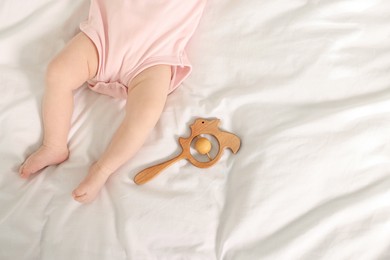 Cute baby and rattle toy on sheets, top view. Space for text