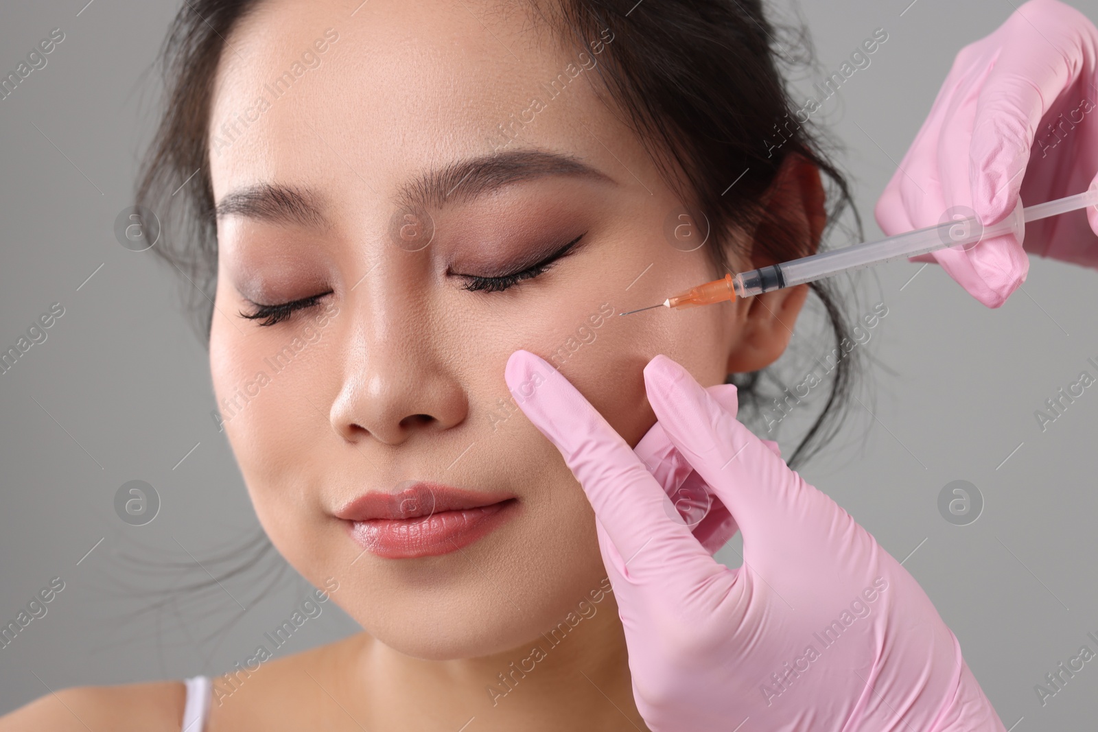 Photo of Woman getting facial injection on grey background, closeup