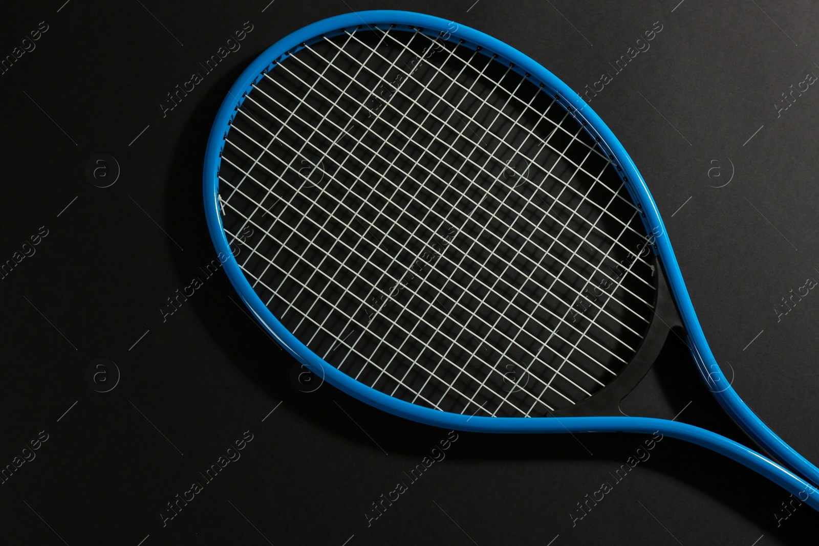 Photo of Tennis racket on black background, top view. Sports equipment