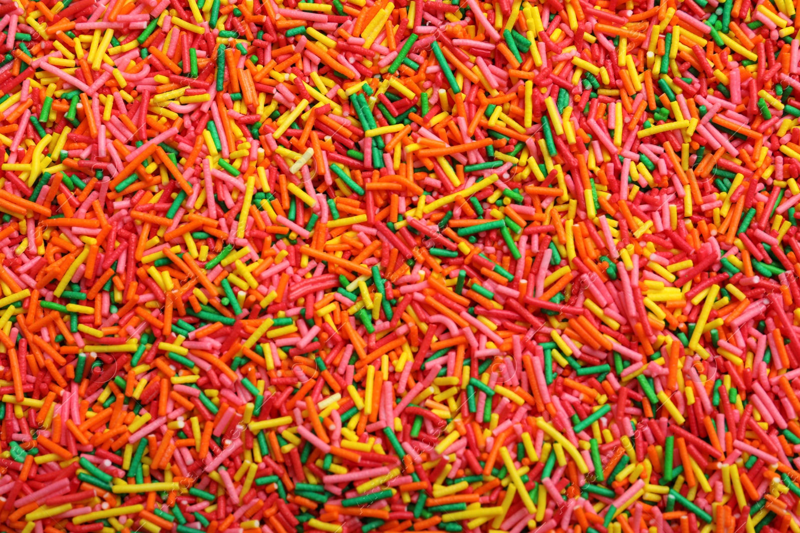 Photo of Bright colorful sprinkles as background, top view. Confectionery decor