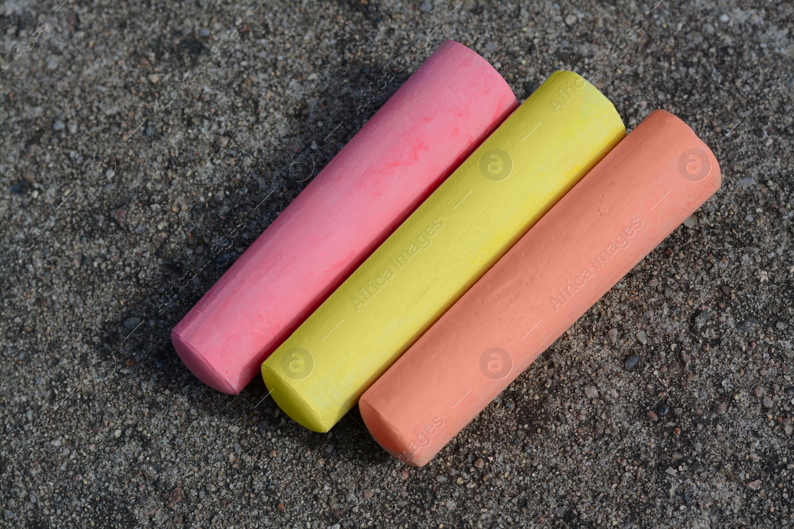 Photo of Colorful chalk sticks on asphalt, flat lay