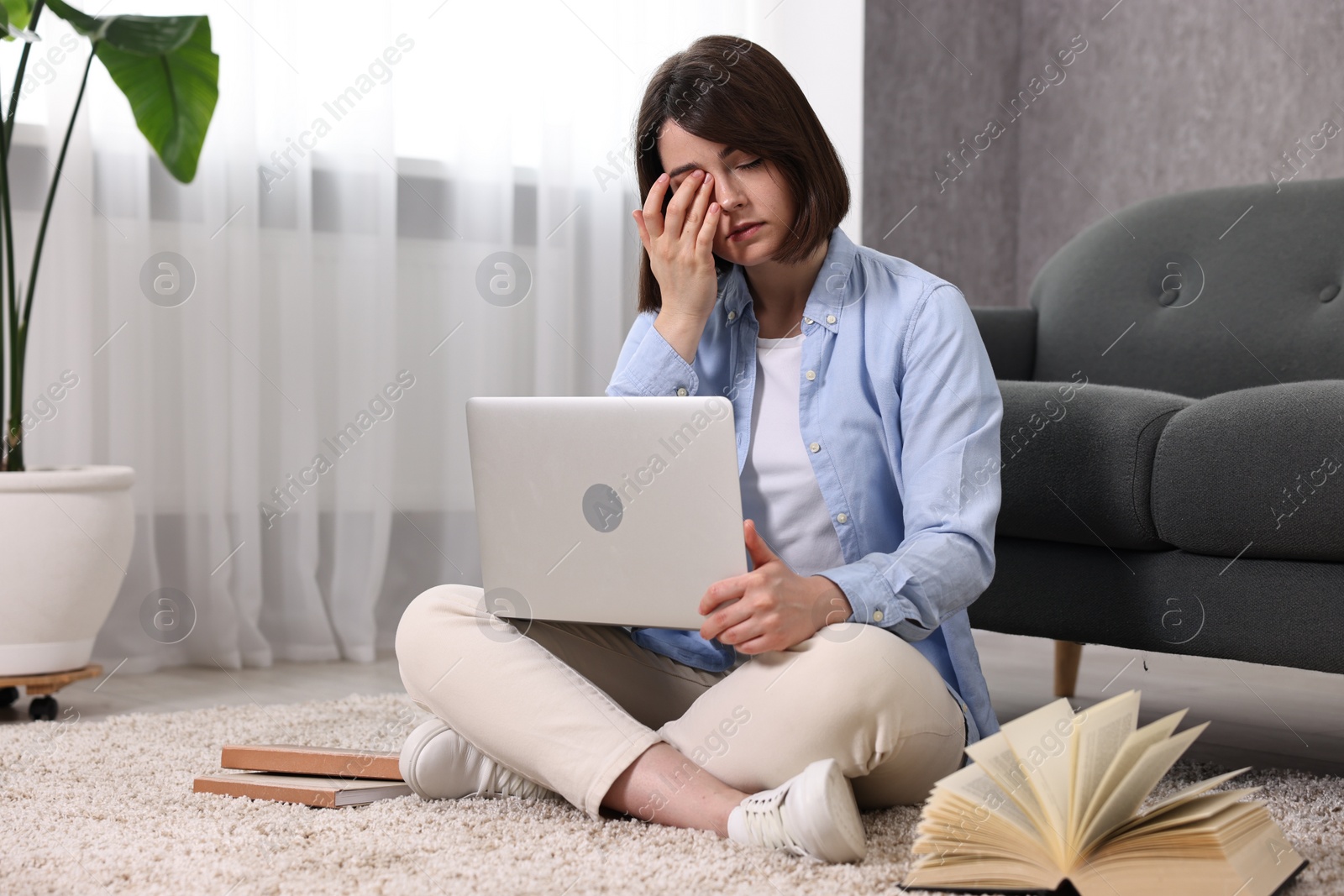 Photo of Overwhelmed woman with laptop sitting on floor indoors