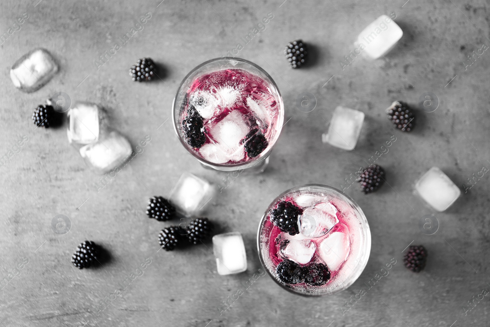 Image of Refreshing blackberry drink with ice on grey table, flat lay 