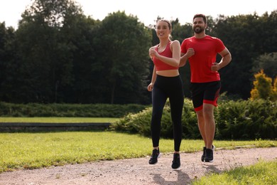 Photo of Healthy lifestyle. Happy couple running outdoors on sunny day, space for text