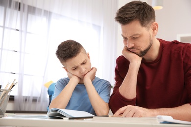 Photo of Dad helping his son with difficult homework assignment in room