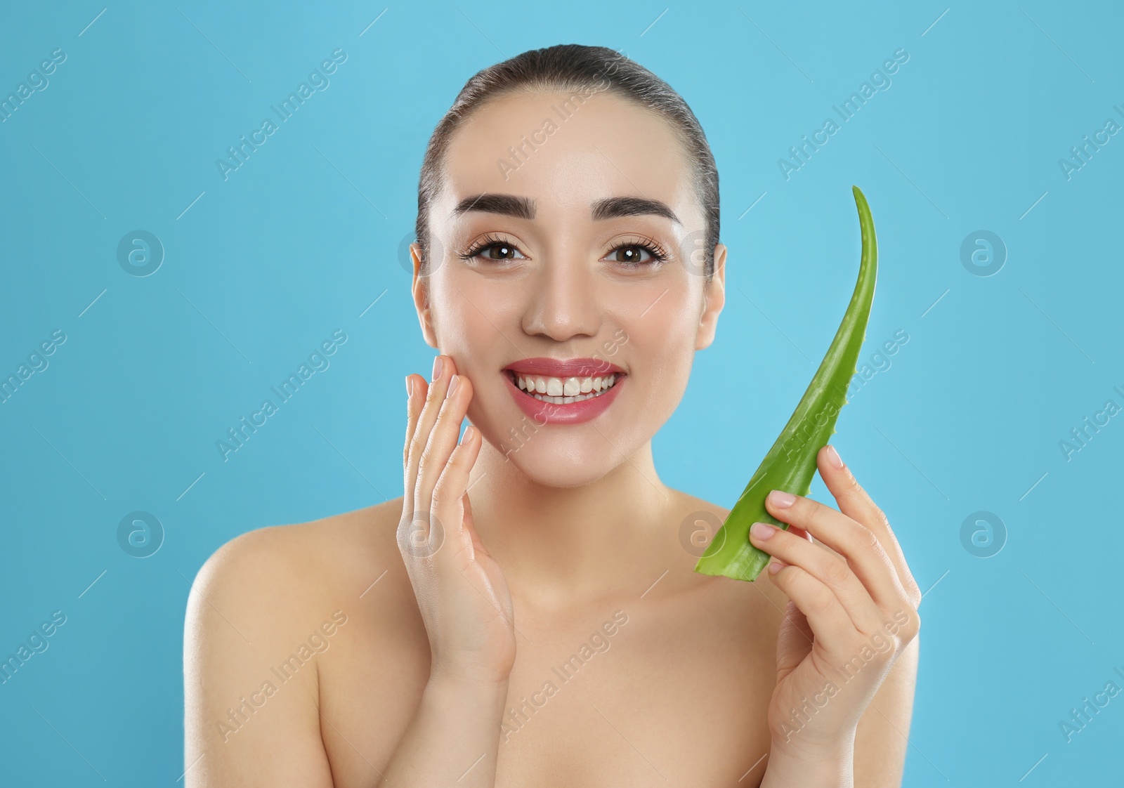 Photo of Young woman with aloe vera leaf on light blue background