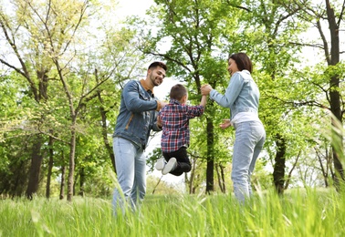 Photo of Little child having fun with his parents in park. Family weekend