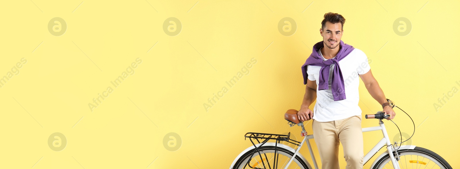 Image of Handsome young man with bicycle on yellow background, space for text. Banner design