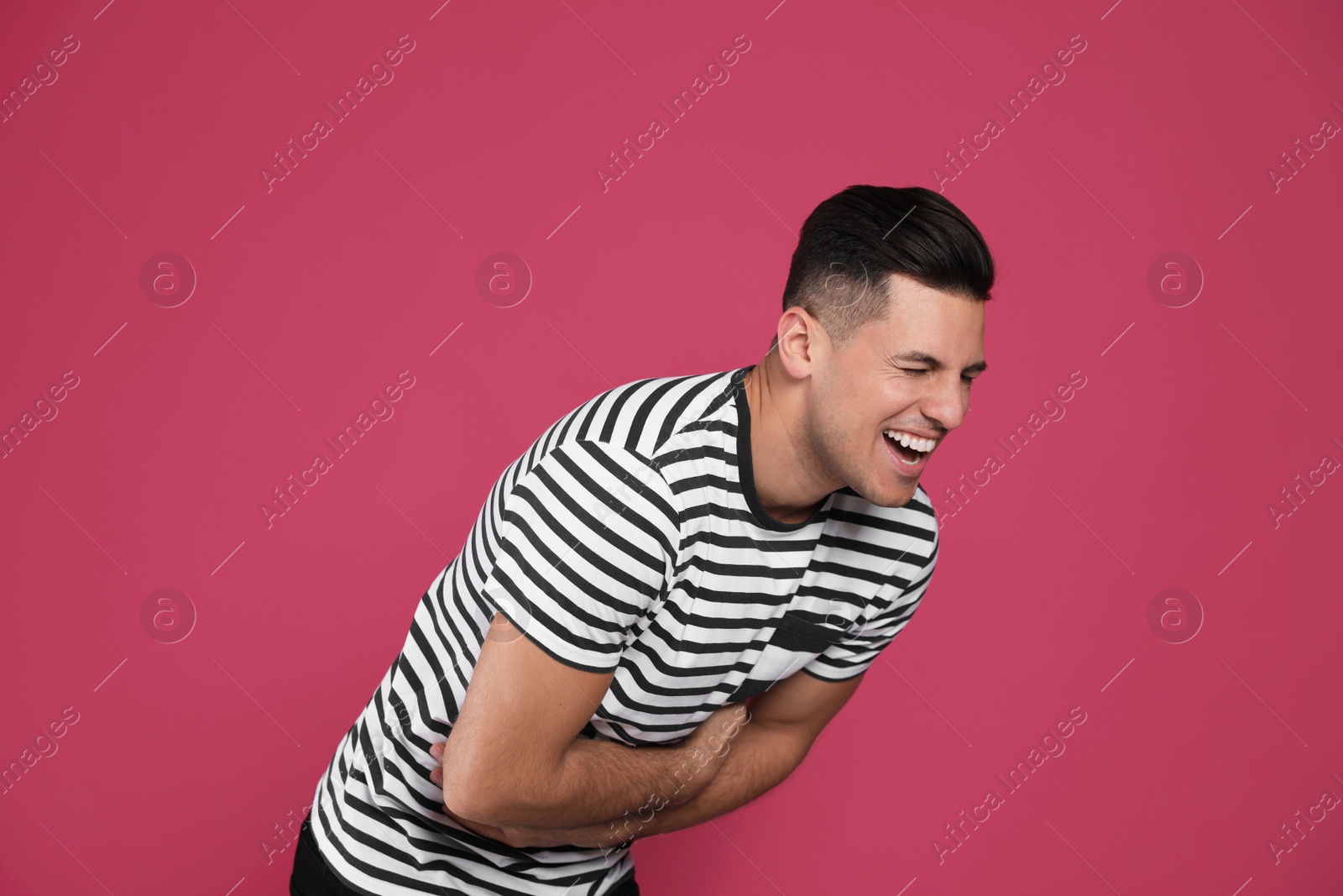 Photo of Handsome man laughing on maroon background. Funny joke