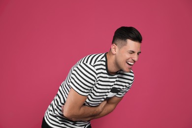 Handsome man laughing on maroon background. Funny joke