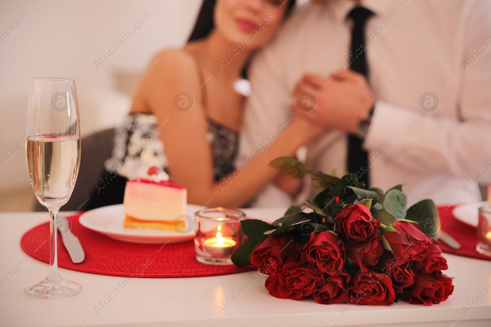 Photo of Happy couple celebrating Valentine's day indoors, focus on bouquet and champagne