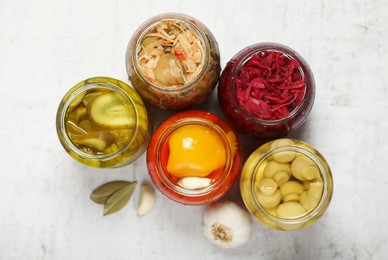 Photo of Many jars with different preserved products on white table, flat lay